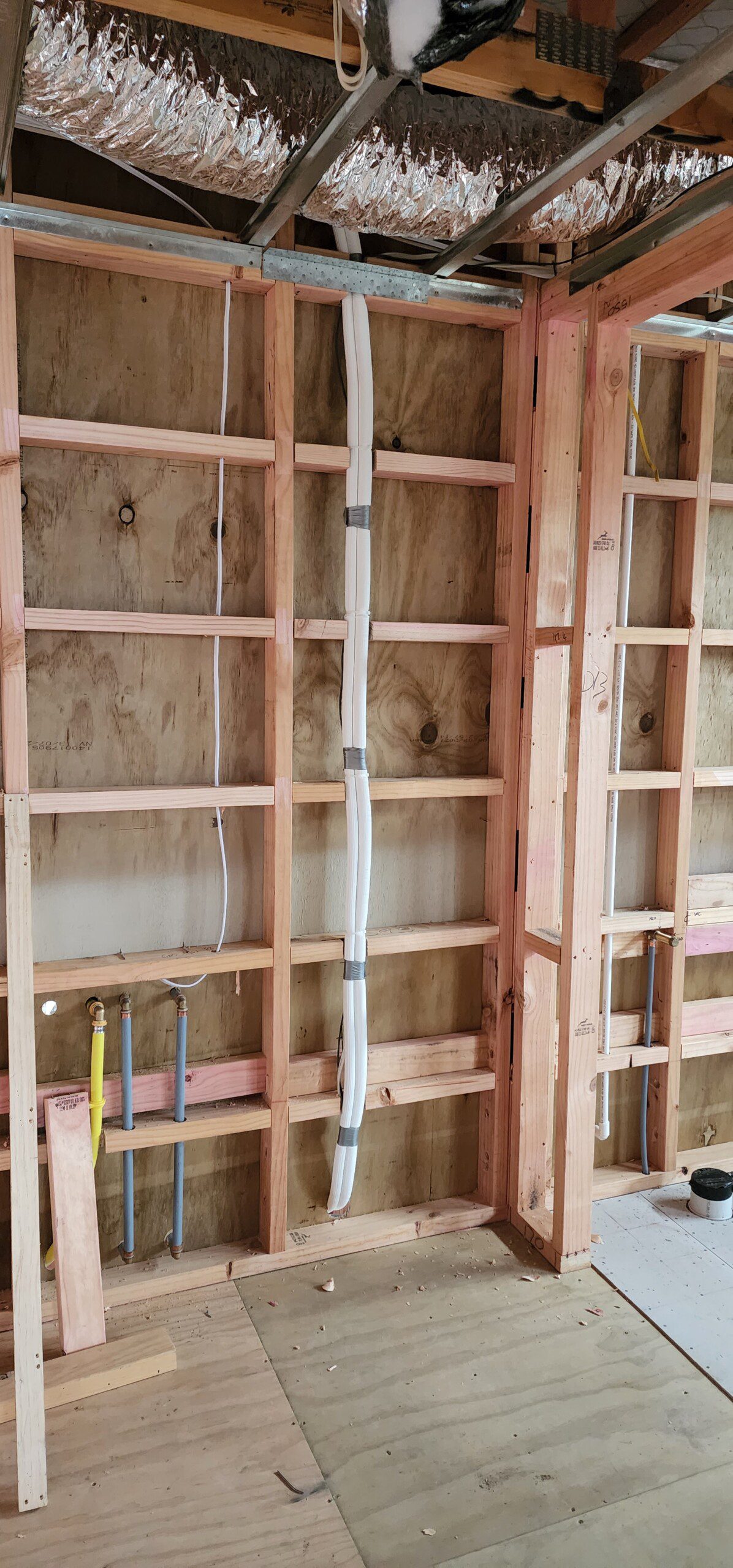 Unfinished room with wooden framing and exposed walls, showing air conditioning installation.