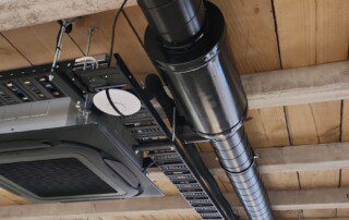 A commercial installation featuring a large pipe, a ceiling fan, and a plant.