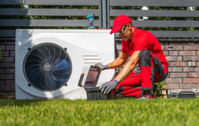Professional Caucasian Heat Pumps Technician in His 40s Installing New Residential Modern Heating Device. HVAC Industry Theme.
