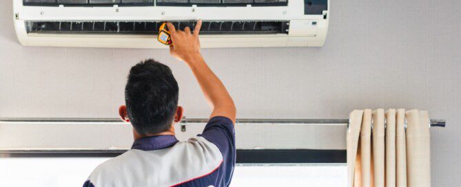 A technician repairs an air conditioner in a room.
