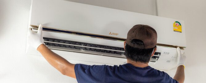 A professional airconditioner man install MITSUBISHI Aircondition on white wall in the house.