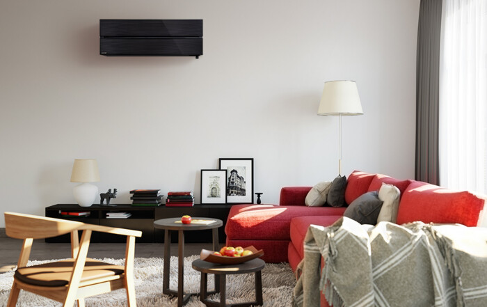 Black Mitsubishi Electric high wall heat pump mounted above a living room sofa